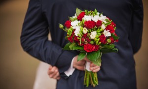 Elegant bride and groom holding bouquet behind his back